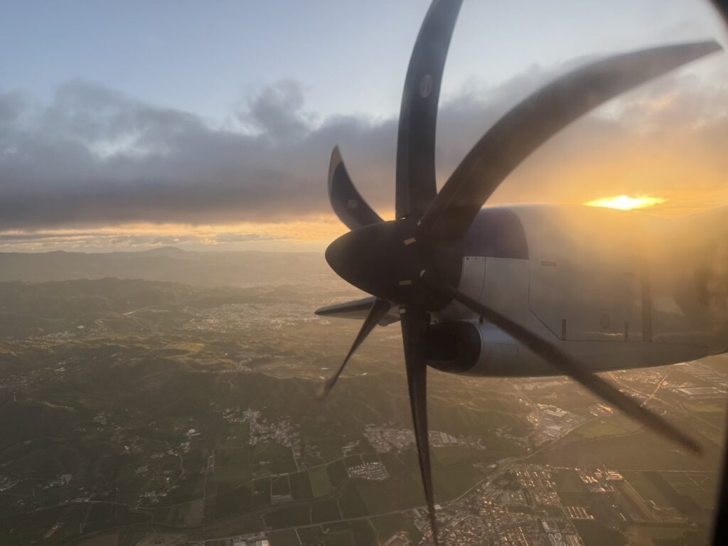 Looking out the aircraft window at the turboprop engine with a pretty landscape below.