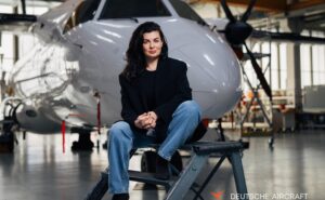 Anastasija Visnakova of Deutsche Aircraft is sitting in front of an aircraft.
