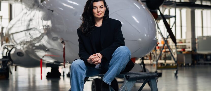 Anastasija Visnakova of Deutsche Aircraft is sitting in front of an aircraft.