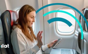 A woman is using her mobile device in flight. The Gilat logo is overlayed on the image.