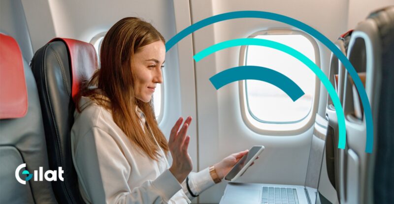 A woman is using her mobile device in flight. The Gilat logo is overlayed on the image.