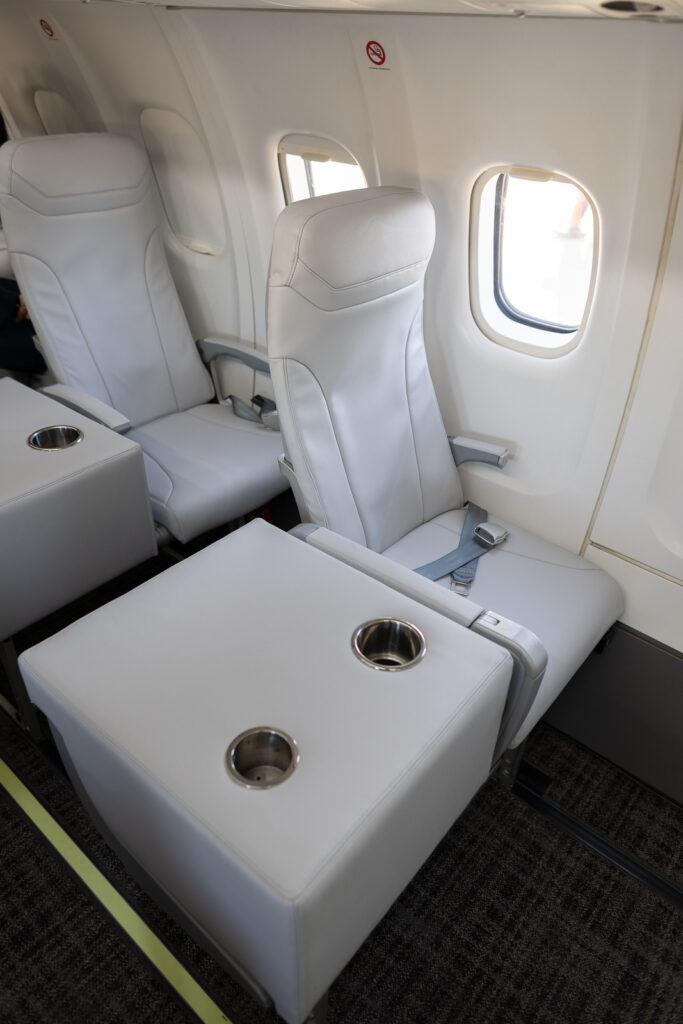The off-white aircraft single seats with a large table and drink holders.