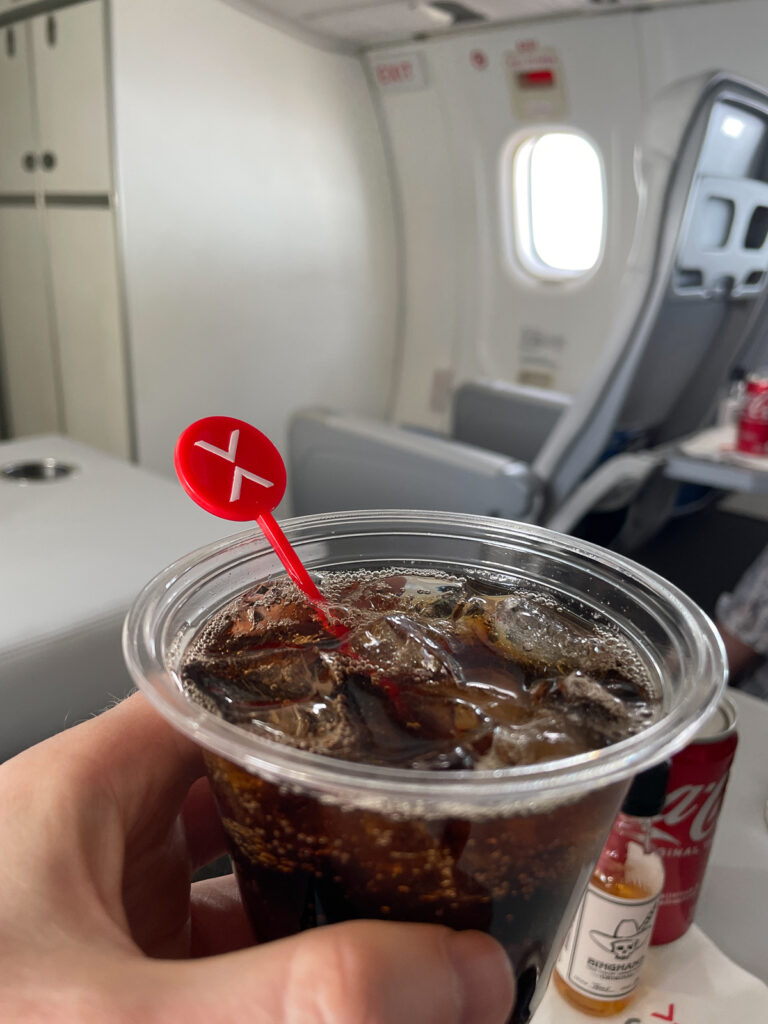 The passenger is holding up a glass of bourbon and coke.