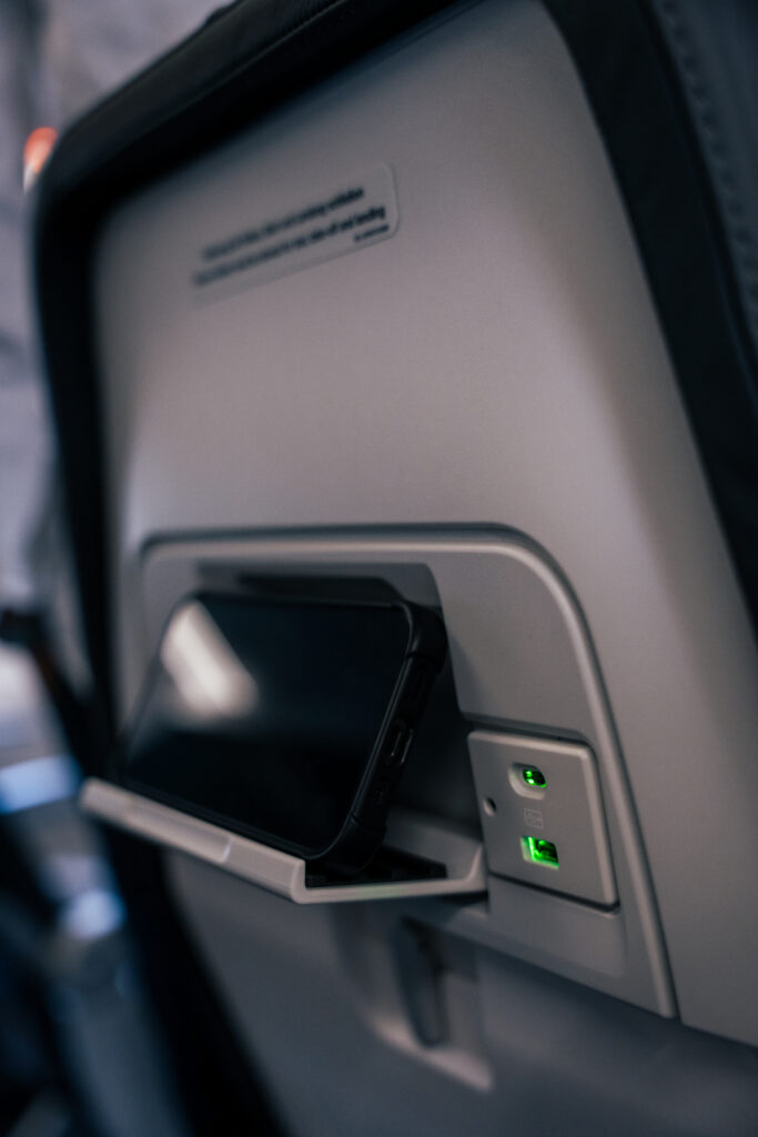 A mobile device is sitting on an seatback PED holder.