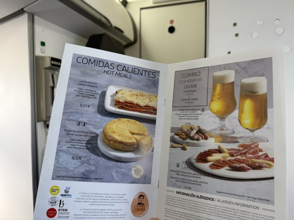 An open menu on the Iberia flight shows various food and beverage options in flight. 
