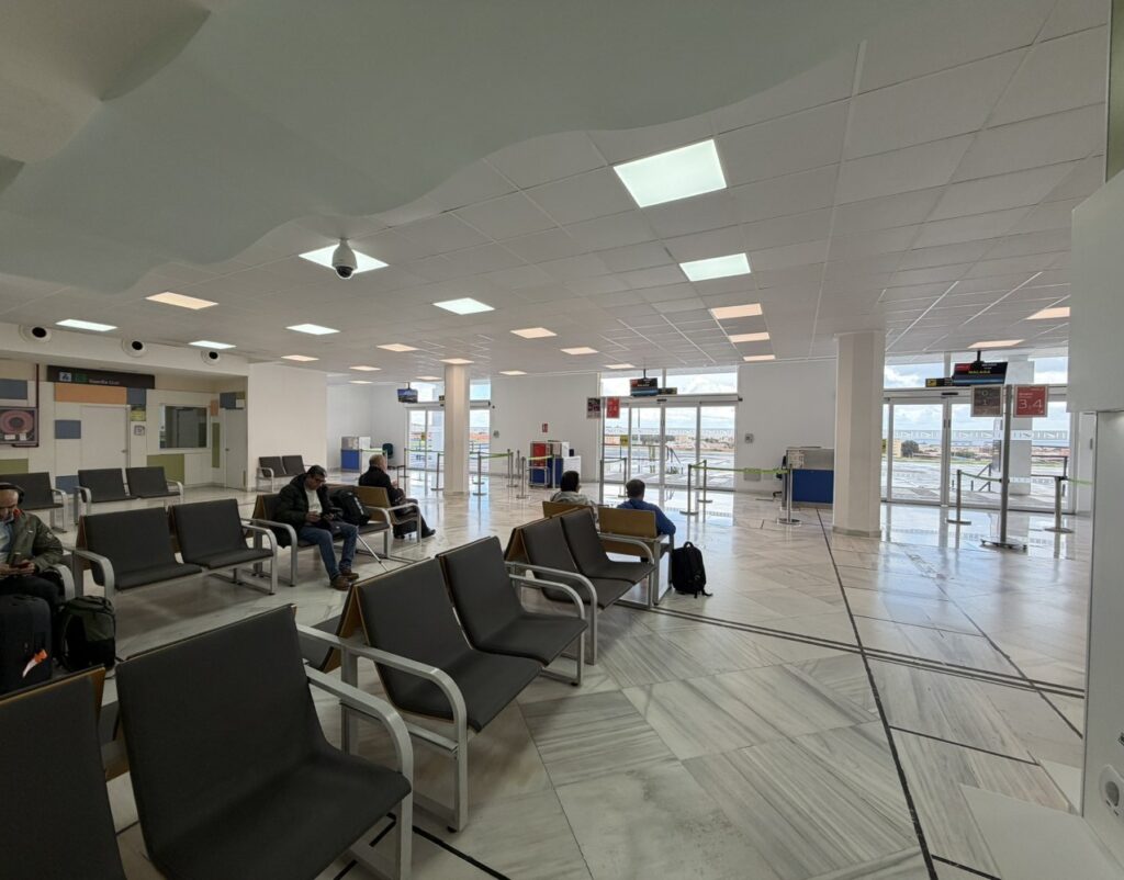 Inside Melilla Airport with various seating options and boarding gates in the background.