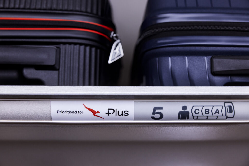 Qantas Economy Plus overhead bins with passengers' luggage prioritized.