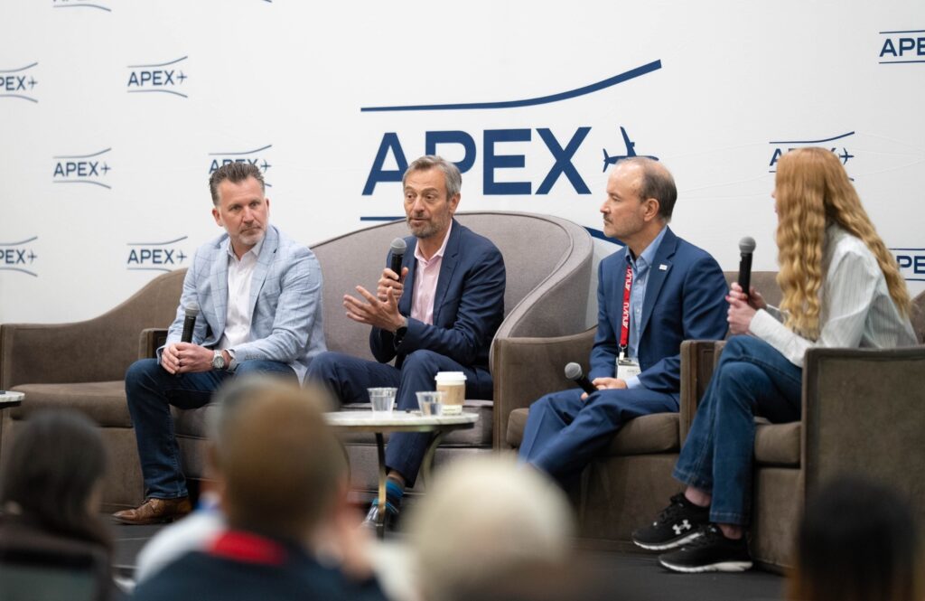 At the mic, Telesat vice president, aviation Philippe Schleret, center, is flanked to his right by Viasat’s vice president of global aviation partners and service delivery, Brian Simone, and to his left by ThinKom Solutions chairman and CTO Bill Milroy. RGN editor Mary Kirby served as moderator.