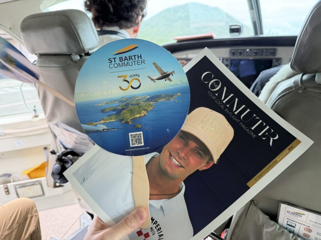 The passenger is holding up an inflight magazine and a fan.