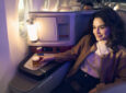 Alaska Airlines International Business Class seat is occupied by a passenger enjoying a drink.