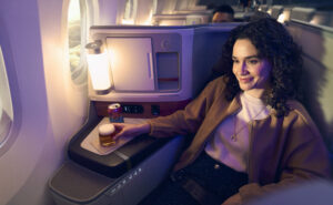 Alaska Airlines International Business Class seat is occupied by a passenger enjoying a drink.