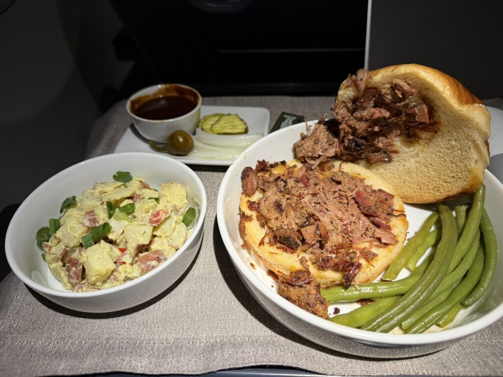 Pecan Lodge smoked chopped brisket sandwich with sides; the sandwich is open to show the plentiful meat