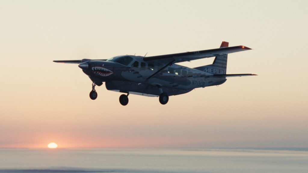 A Cessna Caravan is being controlled with the Merlin Pilot autonomous flight control system as the sun sets in the distance.