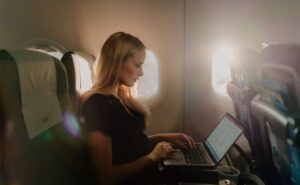 A female passenger is using her laptop in flight with SAS wi-fi powered by Starlink.