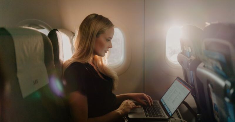 A female passenger is using her laptop in flight with SAS wi-fi powered by Starlink.