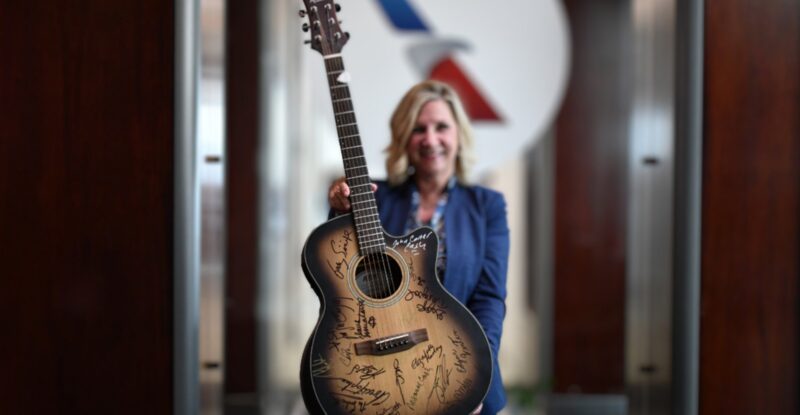 An American Airlines crew member is holding up a guitar