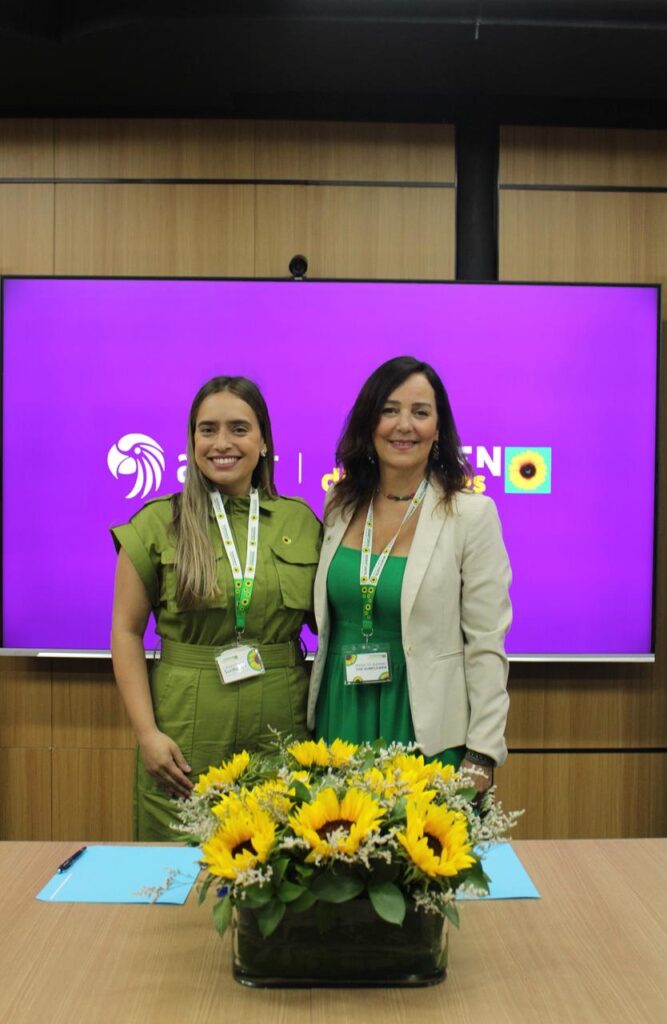 A bouquet of sunflowers is on the table in front of two women: Ivanna Lajara Vp of Culture And HR Management at Arajet, and Flávia Cahu Callafange, Regional Director for Latin America, Hidden Disabilities Sunflower