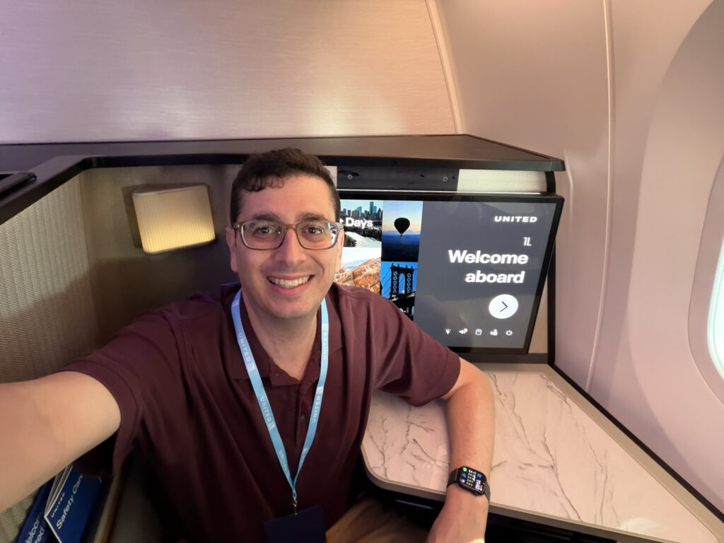 The author, Jason Rabinowitz, smiles while seated in the buddy seat of Polaris Studio, with his back against the IFE screen.