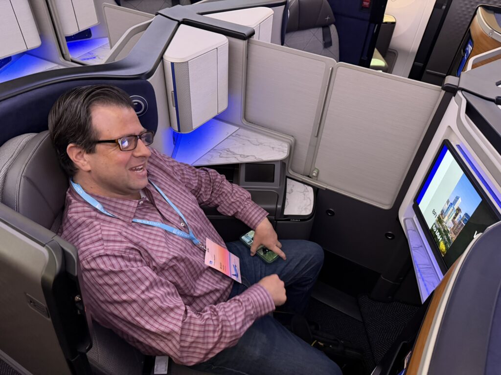 Crankyflier Brett Synder seated in one of the reverse herringbone seats in a center pair. The divider is in view.