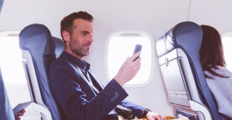 A passenger is using their mobile device in flight.