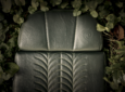 Under the GENCYCLE+ program, seat covers are upcycled into foam cushions for aircraft seats. This image shows an aircraft seat including the foam cushion, with a green seat cover, surrounded by leaves.