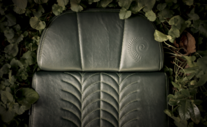 Under the GENCYCLE+ program, seat covers are upcycled into foam cushions for aircraft seats. This image shows an aircraft seat including the foam cushion, with a green seat cover, surrounded by leaves.