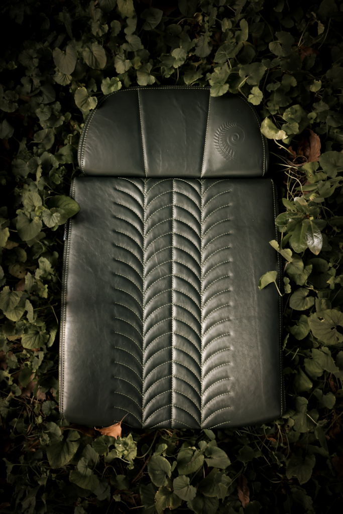 Under the GENCYCLE+ program, seat covers are upcycled into foam cushions for aircraft seats. This image shows an aircraft seat including the foam cushion, with a green seat cover, surrounded by leaves.