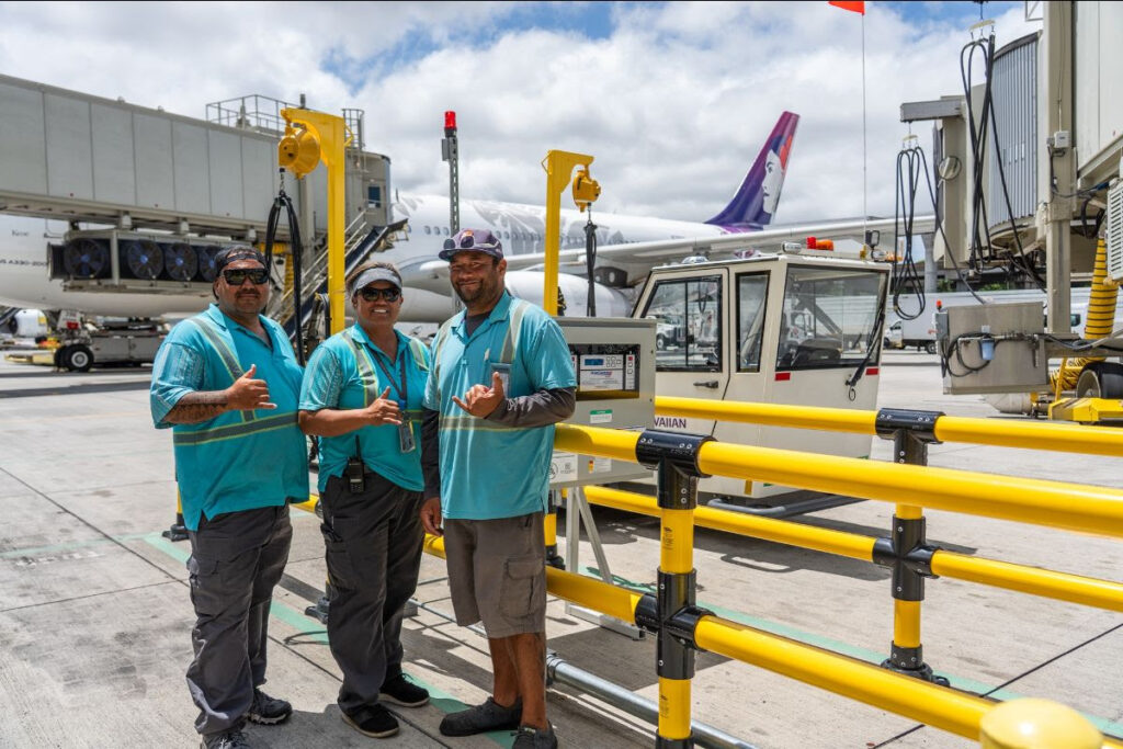 Ground crew standing with the new Hawaiian Airlines electric ground support equipment.