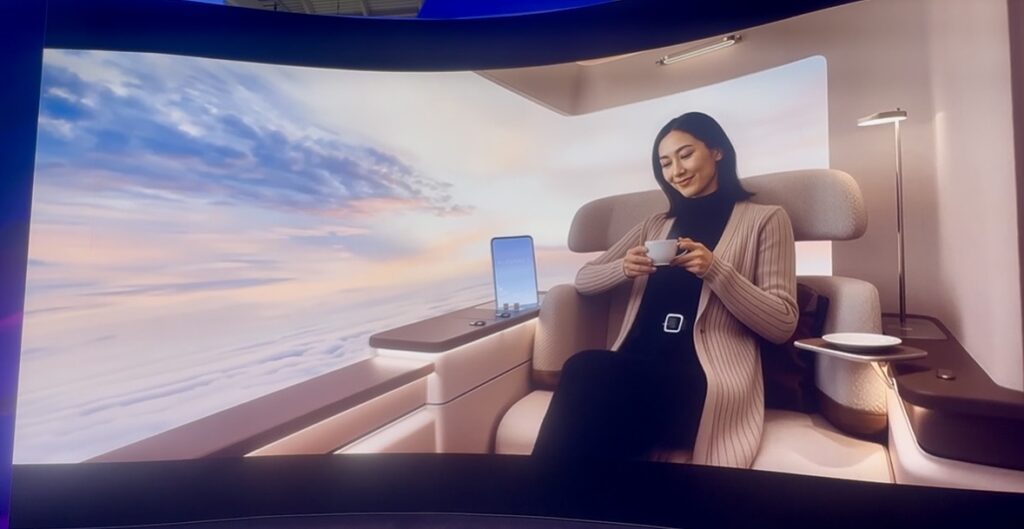 A solo woman traveler enjoys her first class suite with a massive wraparound screen.