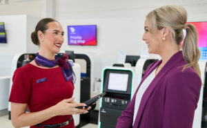 A Virgin Australia crew member is aiding digital check-in of a passenger.