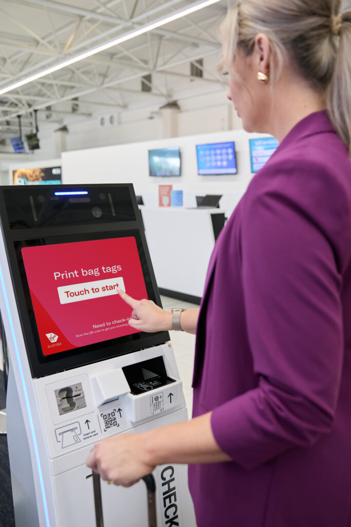 A passenger is using the Virgin Australia bag tag kiosk