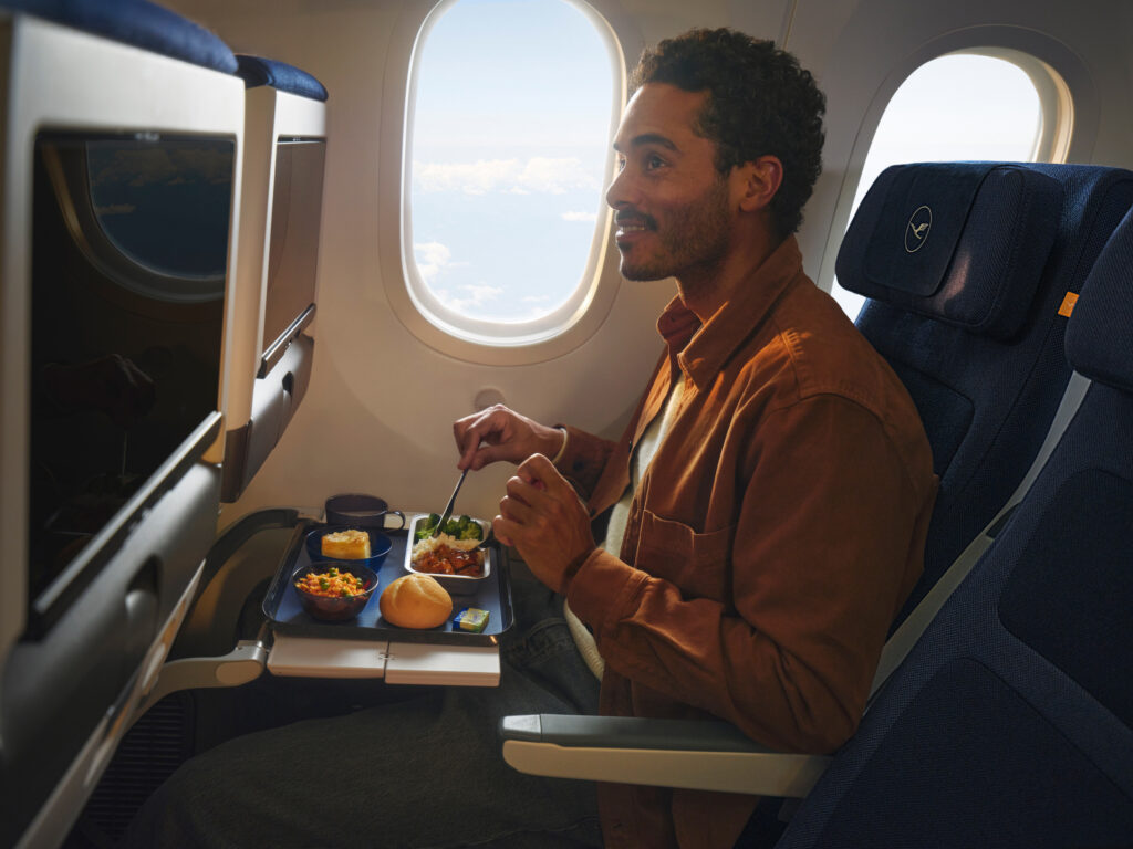 An economy class passenger is enjoying their meal
