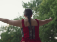 An Indigenous woman is wearing a red dress during a memorial ceremony.