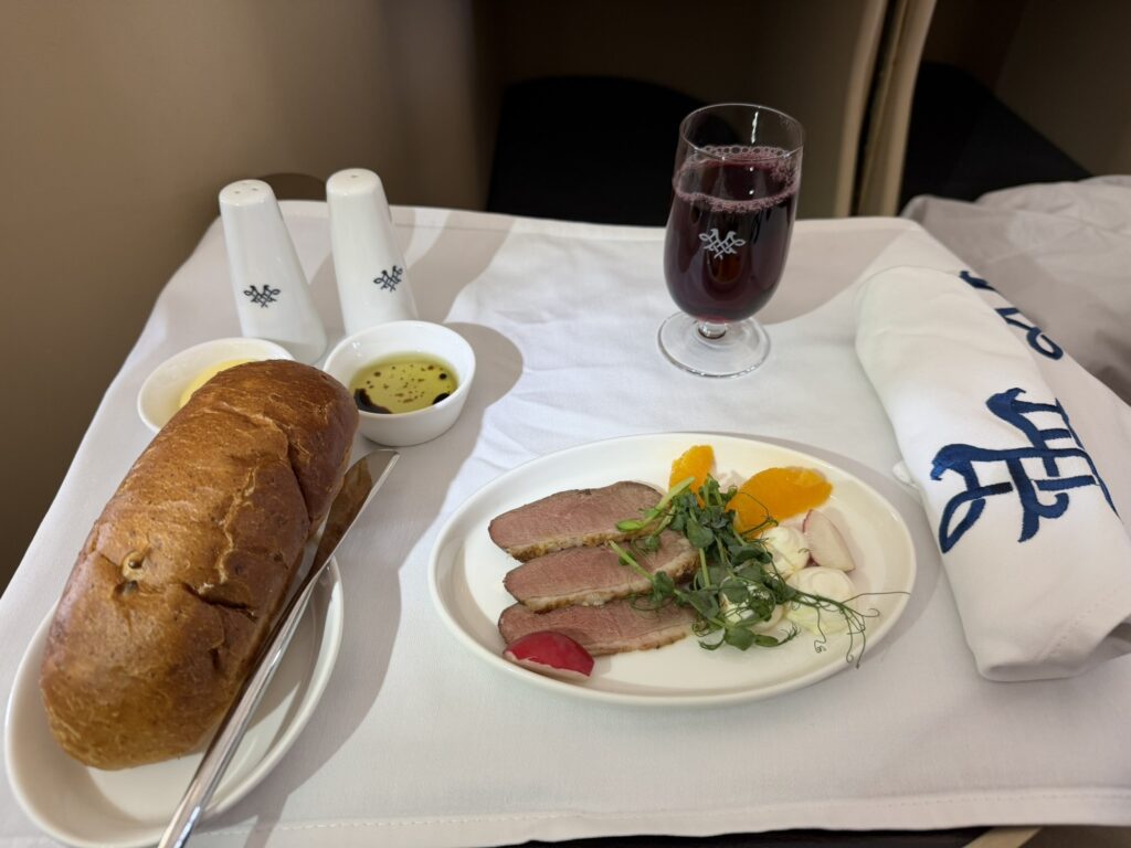 Three slices of red meat, accompanied by a large roll. 