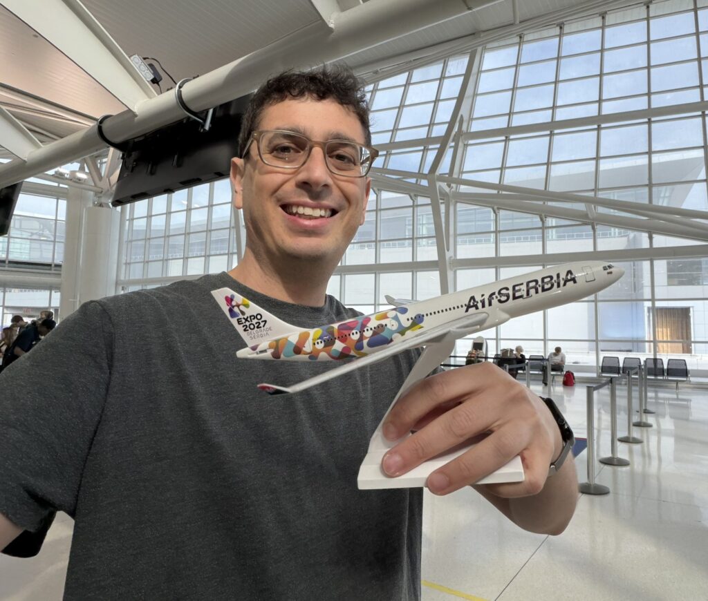 The author, Jason Rabinowitz, holds up an Air Serbia model aircraft at the airport. 