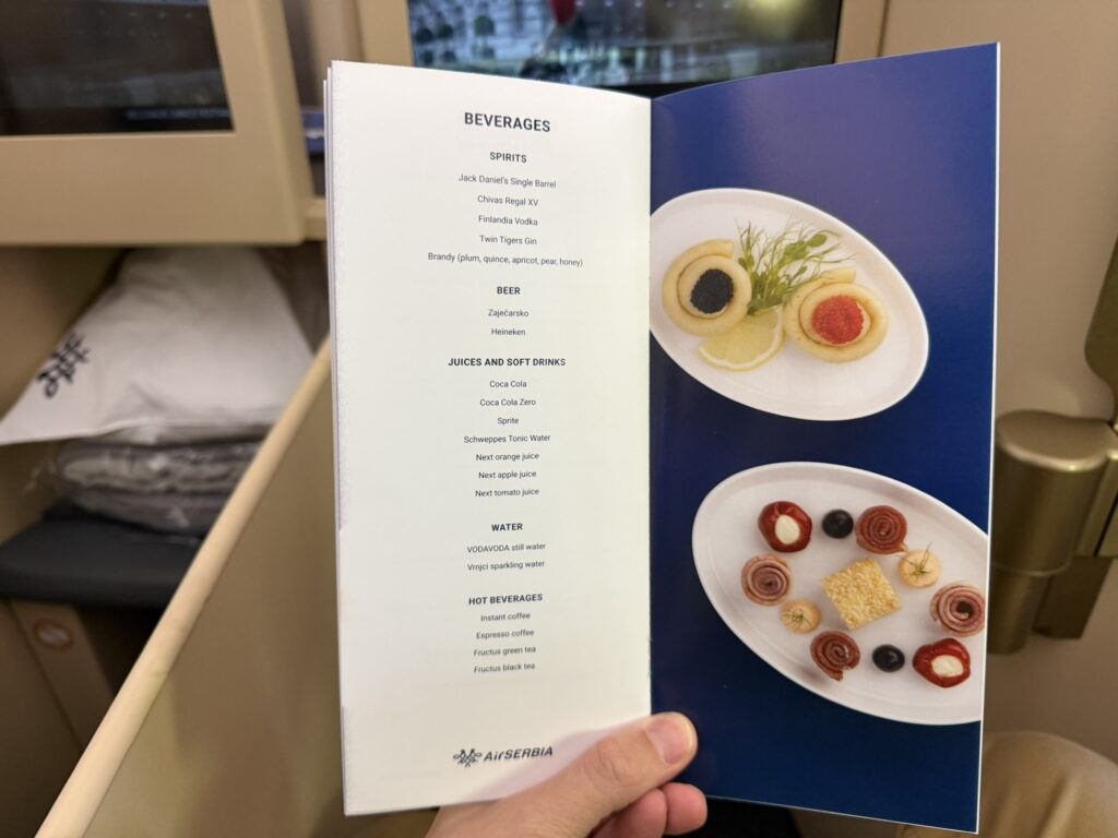 The author holds up the drinks menu while in his seat