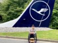 Mary Doyle posing for a photo in front of a Lufthansa aircraft tail.