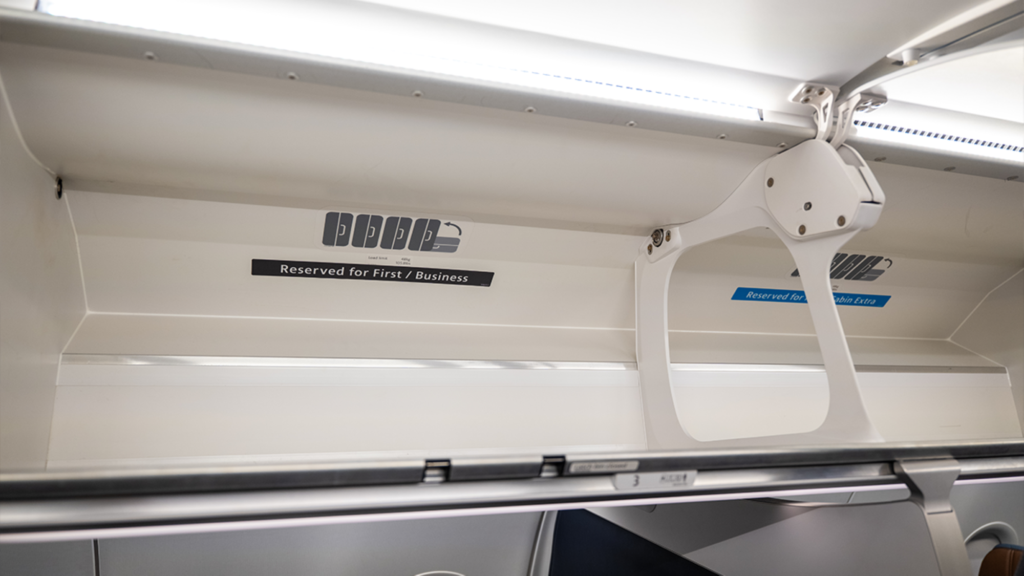 A large flip-up overhead bin, waiting for passengers' bags.