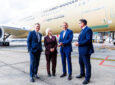 Executives are standing in front of a Qantas aircraft at Melbourne Airport.