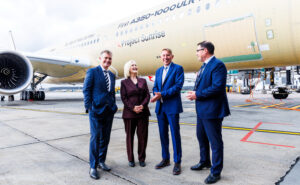 Executives are standing in front of a Qantas aircraft at Melbourne Airport.