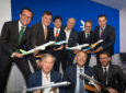 Embraer announces commercial jet sales at the Farnborough International Airshow as various executives pose for a photo holding model aircraft.