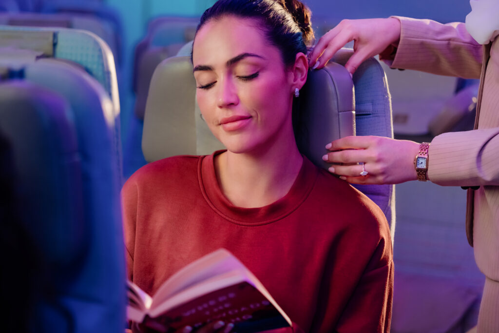 A flight attendant assists a woman using the Emirates U-Dream Headrest
