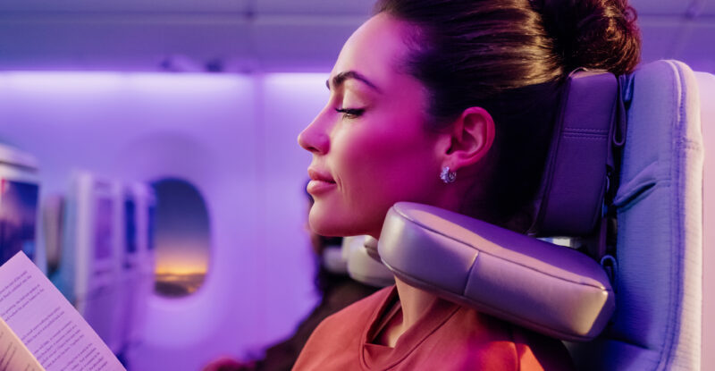 A woman passenger enjoys using the Emirates U-Dream Headrest