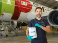 A man is holding up a container of AkzoNobel Aerospace Coatings’ Aerobase UPD formulation in front of a TAP aircraft.