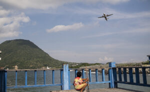 An ATR aircraft flying over Indonesia. A small child looks up.