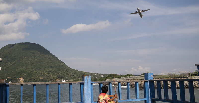 An ATR aircraft flying over Indonesia. A small child looks up.