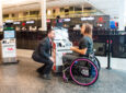 An Air Canada employee is assisting a passenger with a wheelchair at YUL