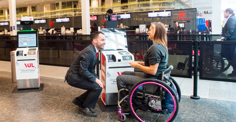 An Air Canada employee is assisting a passenger with a wheelchair at YUL