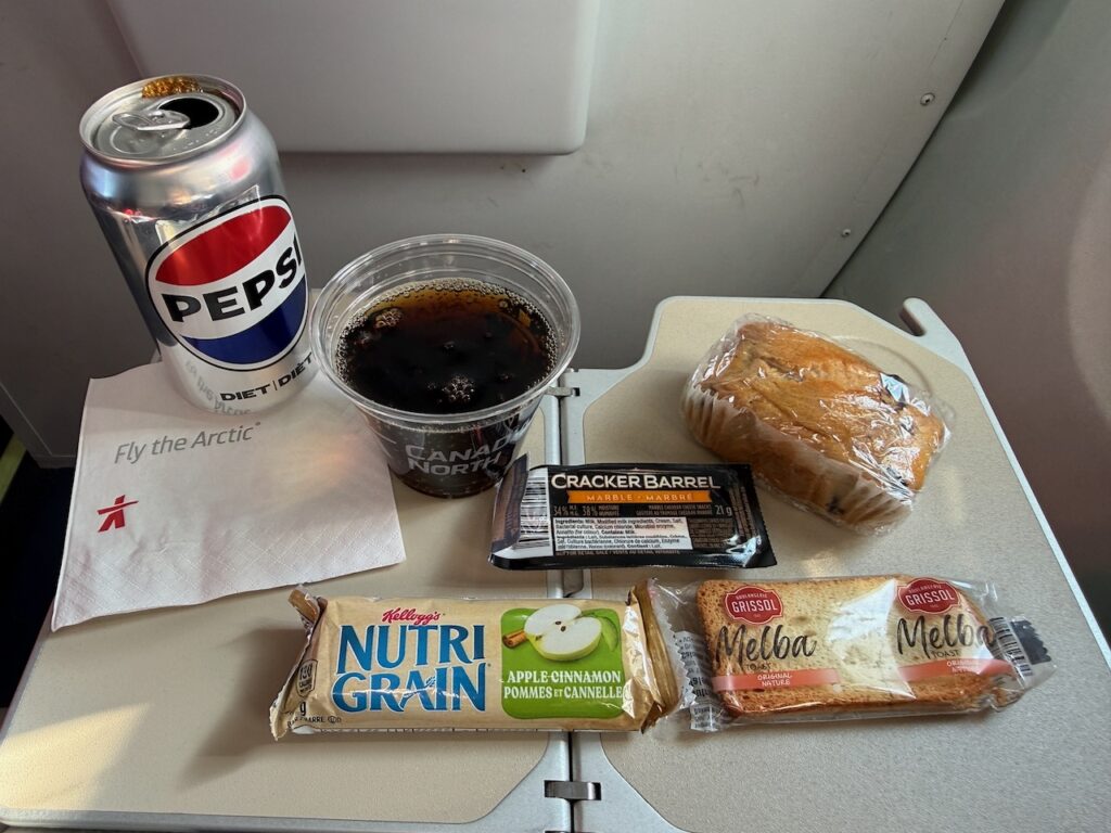The contents of a snack box are displayed on the aircraft tray table.