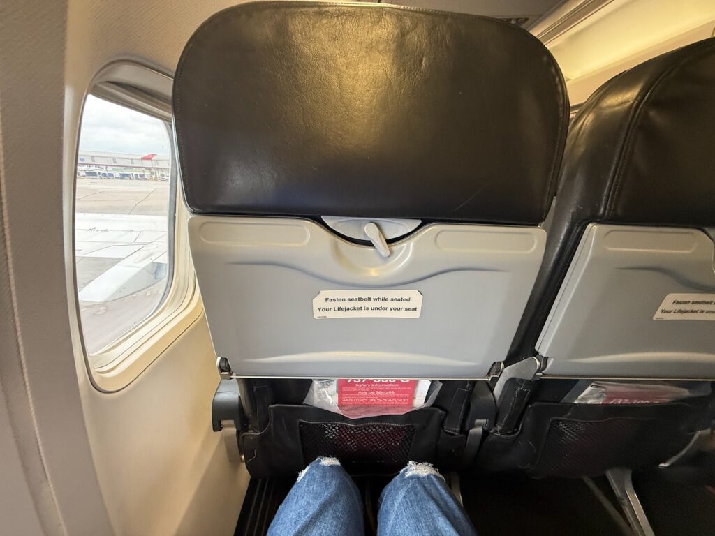 The passenger's knees are seen a good distance away from the seat in front of them.